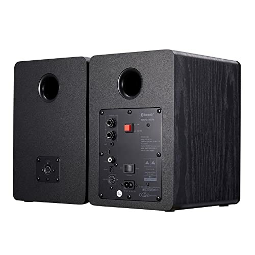 Rear view of black wooden speakers with input ports and controls.