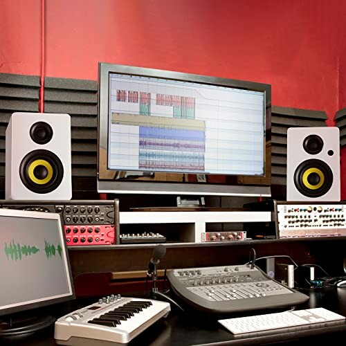 Home recording studio with monitors, speakers, and audio equipment.