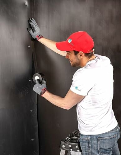 Man in red cap applying tape to a wall