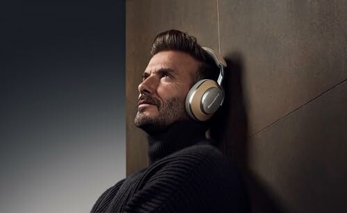 Man wearing headphones leaning against a wall