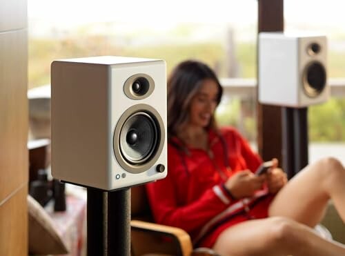 Close-up of modern speakers with a person in the background.