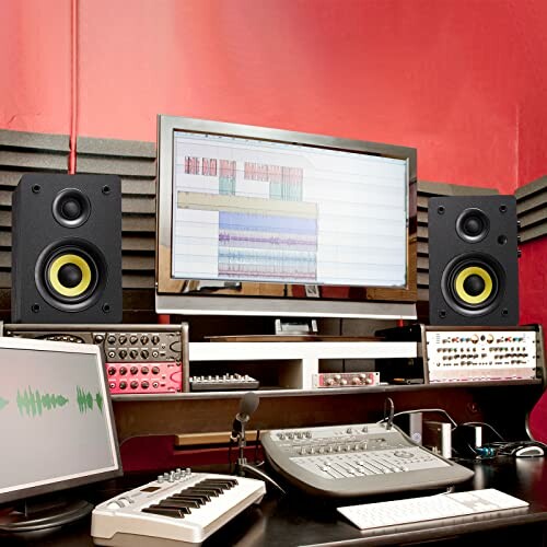 Music production studio with computer, speakers, and audio equipment.