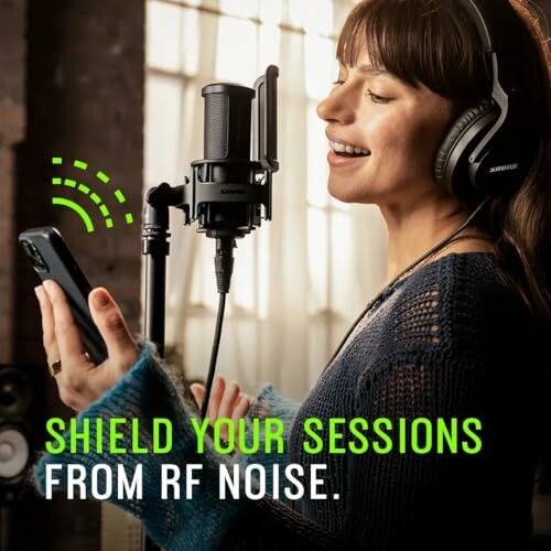 Woman in studio using microphone and phone, shield your sessions from RF noise.